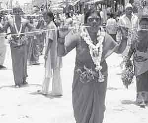 Devotees walk with their cheeks pierced with 16-ft steel rods to offer puja at the Mariyamma temple in Mysore.