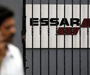 A man speaks on a mobile phone as he walks past an Essar logo in Mumbai in this February 15, 2007 file photo. (Reuters)