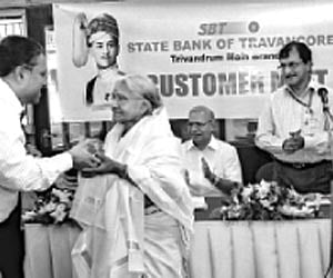 Murugan, managing director of PRS Group of Companies, presenting a memento to Radhamma, the oldest customer of SBT Thiruvananthapuram main branch.
