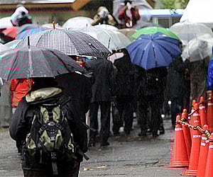 People line up in the rain to participate in a lottery for spectators seats for actress Noriko Sakai's trial in Tokyo. (Photo: AP)