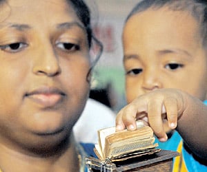 A child runs his fingers through a miniature Bible (inset) at the International Christian Book Fair on Monday