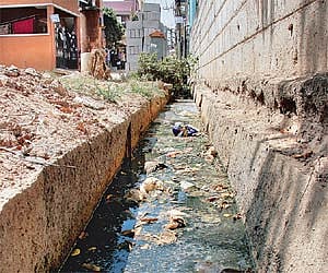 (Left) An uncovered  drainage line in the locality; (Right) Private tankers supplying water and BWSSB work in progress | JITHENDRA M
