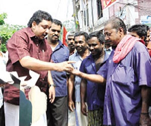 Labour Minister Shibu Baby John distributing cakes to  headload workers of the Palayam  market for refusing to accept ‘nokkukooli’ on Thursday |EPS
