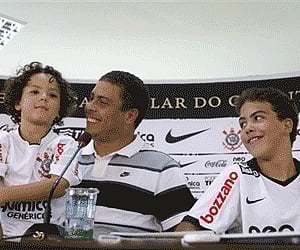 Brazil's soccer star Ronaldo, center, accompanied by his children Alex, left, and Ronald, smiles during a press conference. (AP Photo)
