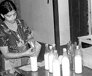 A dairy farmer under Menmma sealing the milk bottles before sending them for distribution.