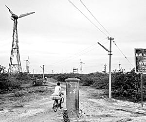A cyclist passing through the Mullakkadu windfarm where many wind turbines have broken leafs.