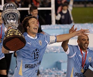 Uruguay's team captain Diego Lugano runs with the trophy after his team defeated Paraguay in the Copa America final soccer match in Buenos Aires. AP