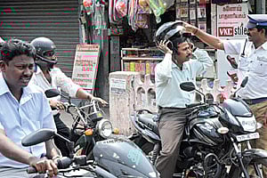 HEAD HUNTING: A motorcyclist who had left his helmet on the tank of his bike instead of on his head is made to wear it by a Chennai Traffic cop on day