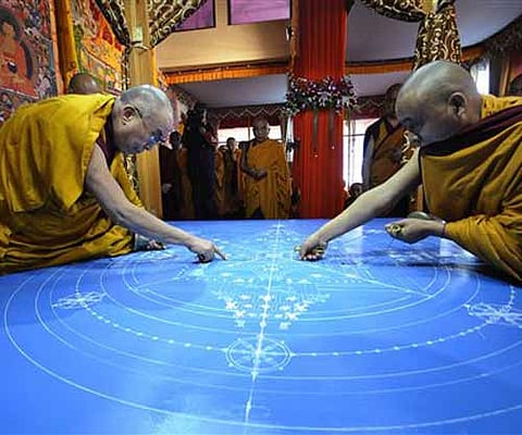 Dalai Lama, left, along with another monk draws a mandala, or a circle, which has spiritual and ritual significance in Buddhism. AP