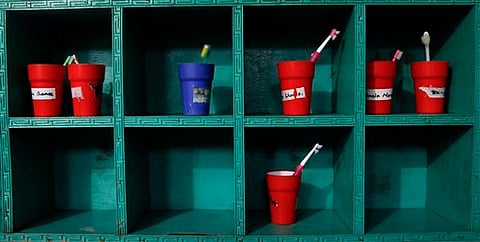 Colored tumblers with name tags pasted on them hold toothbrushes (AP)