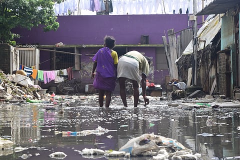 A man and woman walking through the sewage water filled up on the road which leads to their house.    ( Picture: K S Aditya Rao)