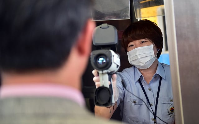 An official (R) checks the body heat of South Korean Unification Minister Hong Yong-Pyo (L) as he visits the South's CIQ (Customs, Immigration, Quarantine) gate connecting North Korea's Kaesong Industrial Complex at the inter-Korean transit office in Pa