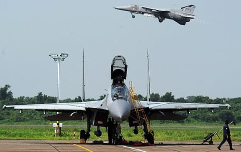 Indian Air Force (IAF) engineers prepare a Sukhoi-30 fighter jet ahead of a drill as a MIG-27 flies overhead during a drill for Air Force Day celebrations in Kalikunda. (AFP)