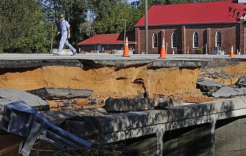 A man walks across a road damaged by floodwaters caused by rain from Hurricane Matthew in Fayetteville, N.C. |AP