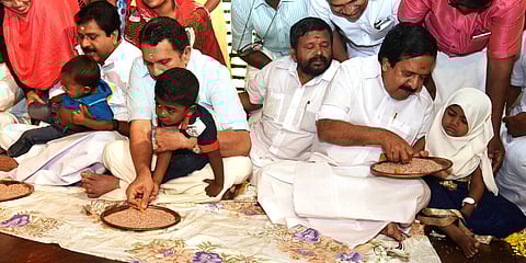 Opposition leader Ramesh Chennithala, MLAs K Muraleedharan and V S Sivakumar teaching children their first letters | Express
