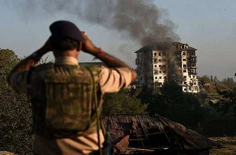 A security officer watching through the binocular at multi-storied government building where some militants were holed up at Pampore. (File | PTI)