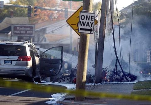 Smoke pours from the smoldering remains of a small plane that crashed on Main Street in East Hartford  | AP