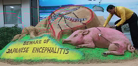 Artist Subal Maharana creates a sand sculpture on JE disease in Bhubaneswar on Saturday. | EPS