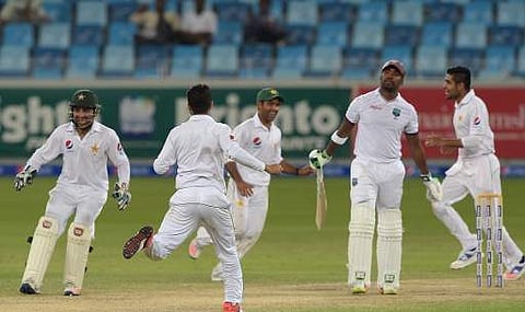 Pakistani cricketers celebrates after the dismissal of West Indies batsman Darren Bravo (2R) for 87 runs on the third day of first day-night Test between Pakistan and the West Indies. | AFP