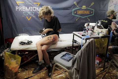 A woman gets a new tattoo on her thigh as she pauses to take a break. (Photo | AP)