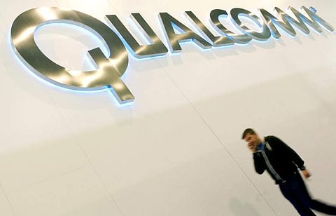 A man walks past a Qualcomm advertising logo at the Mobile World Congress at Barcelona. ( File photo | Reuters)