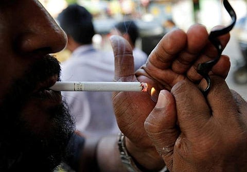 A man lights a cigarette along a road in Mumbai, India | Reuters