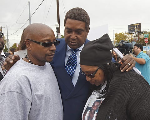 Attorney John Burris, center, comforts Robert and Deborah Mann, family members of Joseph Mann, who was killed by Sacramento Police in July, after a news conference Monday, Oct. 3, 2016. | AP
