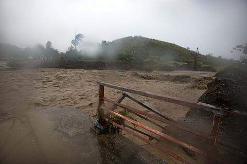 People watch from the other side of the La Digue river as water roars past the destroyed Petit Goave bridge, as Hurricane Matthew passes over, in Petit Goave, Haiti, Oct. 4, 2016.  | AP