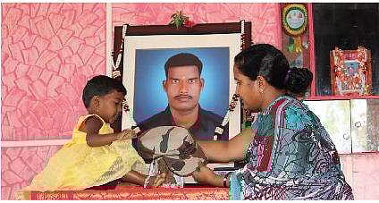 Siachen martyr Hanumanthappa Koppad’s wife Mahadevi and daughter Netra stand before his portrait at their house at Betadur village near Hubballi | D Hemanth