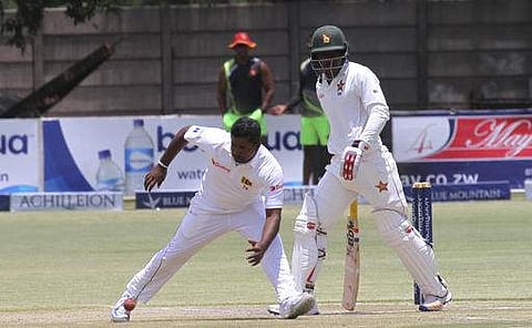 Sri Lanka captain Rangana Herath, left, goes for the ball as Zimbabwe batsman Brian Chari looks on during the test cricket match against Zimbabwe. | AP