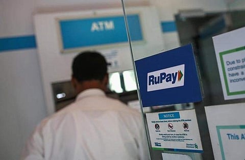 A RuPay sign is seen on the door of an automated teller machine (ATM) while a user is seen, at a commercial building in Mumbai September 11, 2014. | Reuters