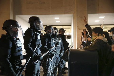 Police stand in front of people who march through downtown Portland, Ore., to protest of the election of president-elect, Donald Trump. | AP