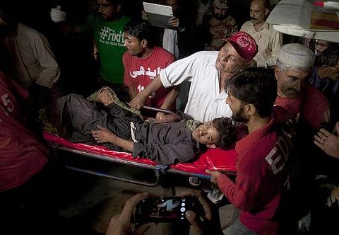 Pakistani rescue workers and volunteers carry an injured victim of a bomb blast at a Sufi shrine, upon his arrival at a local hospital in Hub town near Karachi. (Photo | AP)