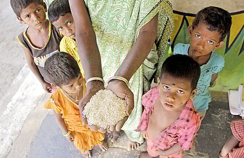 An anganwadi teacher holds rice from school rations in her hand as students surround her in Lokari. K village in Narnoor manadal of Adilabad district | Sathya keerthi