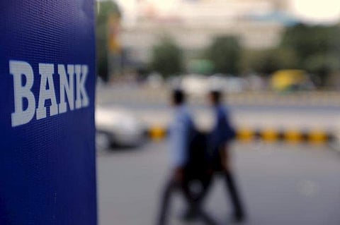 Commuters walk past a bank sign along a road in New Delhi in this November 25, 2015 file photo | REUTERS