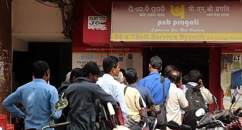 People wait outside an ATM kiosk. (File | EPS)