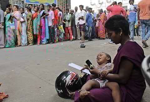 A woman waiting with her baby as her husband stands in a queue at a bank near Chennai Harbour on Wednesday | ASHWIN PRASATH