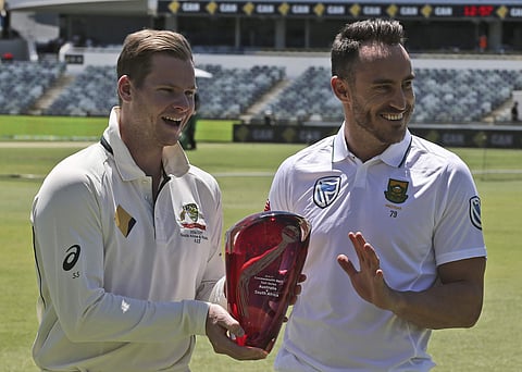 Cricket captains Australia's Steve Smith, left, and South Africa's Faf du Plessis laugh about touching the test series trophy in Perth, Australia. | AP