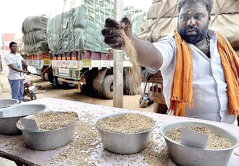 A shop owner checks the quality of paddy at Red Hills, where fully-loaded lorries were stranded on Monday | P jawahar