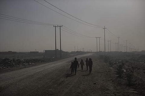 Children walk among smoke from burning oil fields in Qayara, south of Mosul, Iraq, Tuesday, Nov. 22, 2016. (AP)