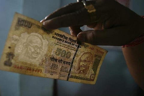 An employee checks a 500 Indian rupee note at a cash counter inside a bank in Agartala. (File Photo | Reuters)