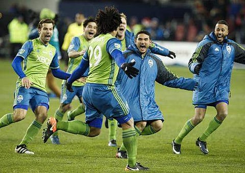 Seattle Sounders players chase defender Roman Torres (29) after he scored the game-winning shootout goal to defeat the Toronto FC during shoot out MLS Cup soccer final. | AP
