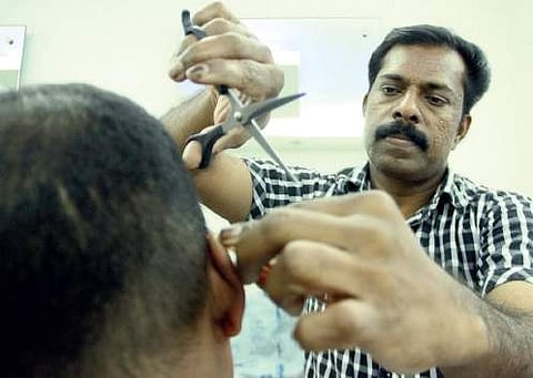 N K Babu giving a hair cut to a customer at his salon  Melton Antony