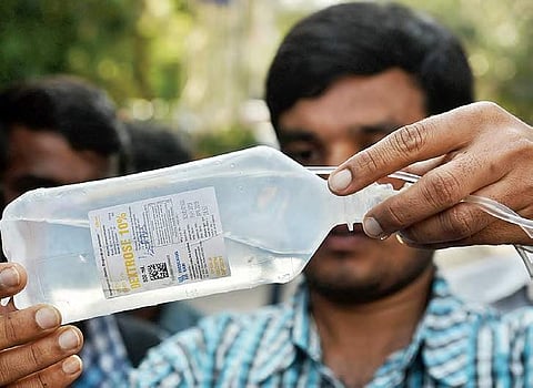 A staffer at the Gandhi Hospital inspects the saline bottle which had the particulate matter, in Hyderabad on  Thursday | R Satish Babu
