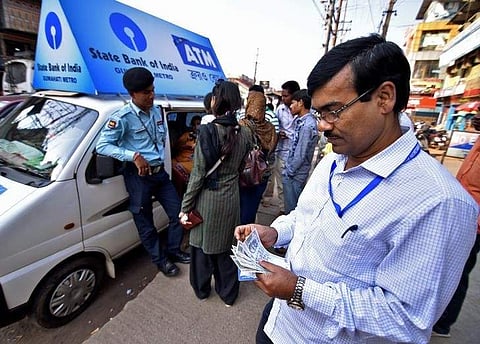 A man counts 100 Indian rupee banknotes after withdrawing them from a mobile ATM van in Guwahati, India, November 25, 2016. | Reuters