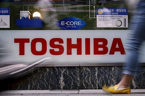 Pedestrians walk past a logo of Toshiba Corp outside an electronics retailer in Tokyo, Japan, June 25, 2015. REUTERS