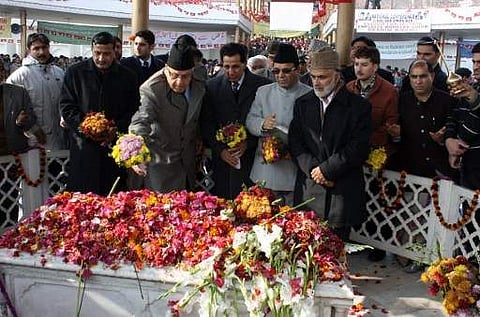 Indian Minister for New and Renewable Energy Farooq Abdullah (C) lays a floral tribute on the grave of his father and former Jammu and Kashmir Chief Minister Sheikh Mohammad Abdullah. | AFP