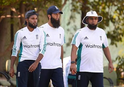 England's cricketer Adil Rashid, Moeen Ali, and bowling coach Saqlain Mushtaq walk towards the nets during a training session at the Punjab Cricket Association Stadium in Mohali.  | AFP