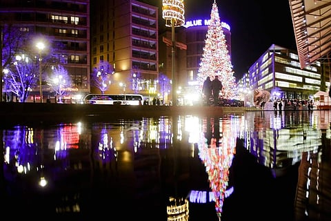 Visitors walk in front of the illuminated Christmas tree near the Christmas market at the Potsdamer Platz square in Berlin. (Photo | AP)