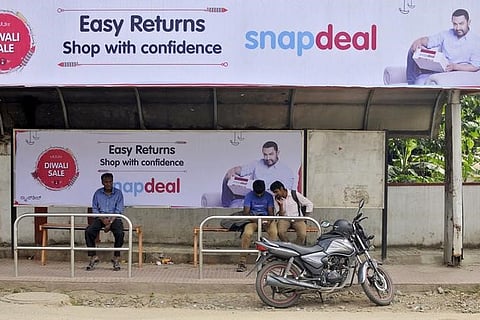 Commuters sit at a bus stop adorned with an advertisement of Indian online marketplace Snapdeal featuring Bollywood actor Aamir Khan, in Bengaluru, India, October 15, 2015. | File Reuters